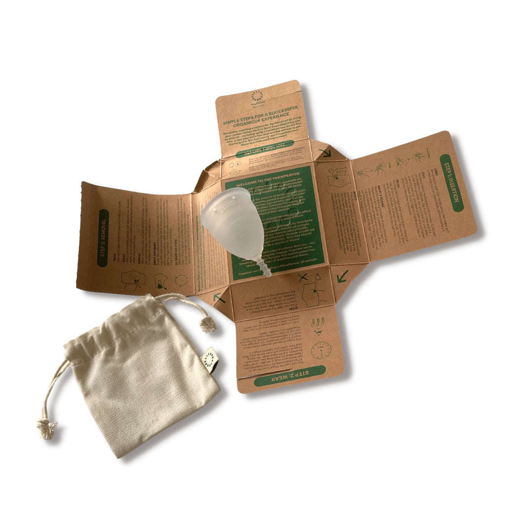 AllMatters silicone menstrual cup unboxed with detailed information printed on inside of packaging and silicone menstrual cup atop and cream colored carrying pouch to the lower left.