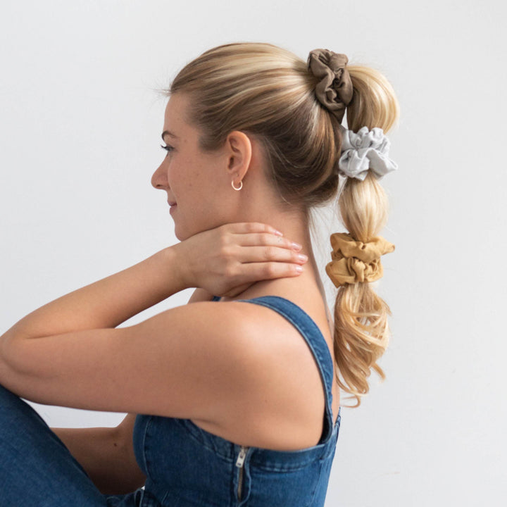 Woman with ponytail secured by 3 hair scrunchies.